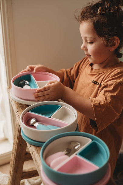 Child enjoying silicone dinnerware with multifunctional plate set showing vibrant pink and blue colors.