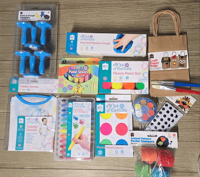 Assorted art supplies including paint sticks, stampers, and paper bags on a wooden surface.