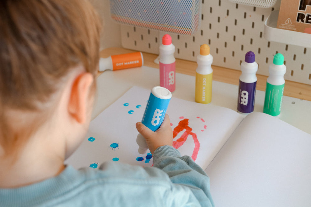 Child using Dot Paints from a 6 Dot Markers set to create art on a page with vibrant colors.
