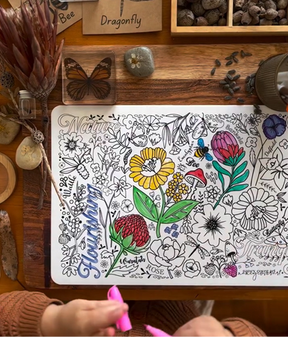 Coloring book with floral designs on a wooden table with stamps and natural elements.