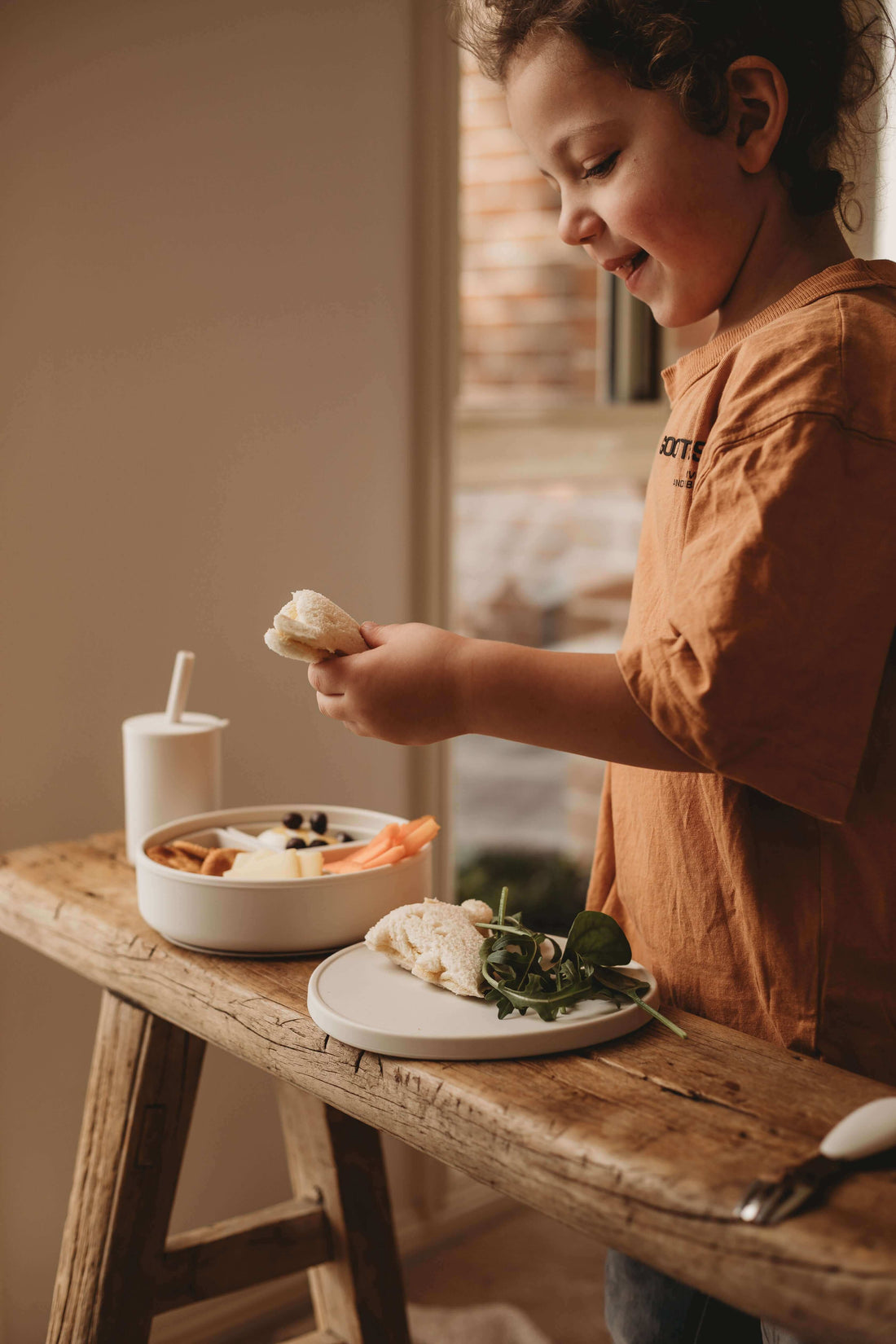 Healthy snacks for kids 1-6 years, boy enjoying nutritious food with fruits and vegetables on a wooden table.