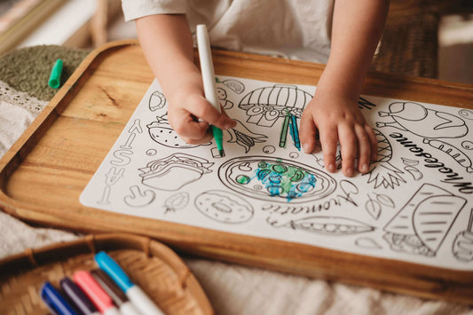 Child using quality art supplies for children to color a creative drawing on a wooden table.