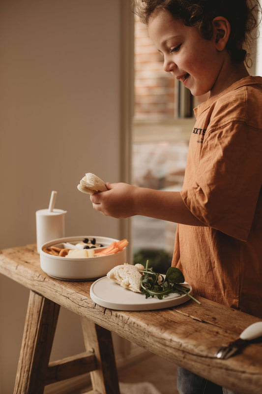 Healthy snacks for kids 1-6 years, boy enjoying nutritious food with fruits and vegetables on a wooden table.