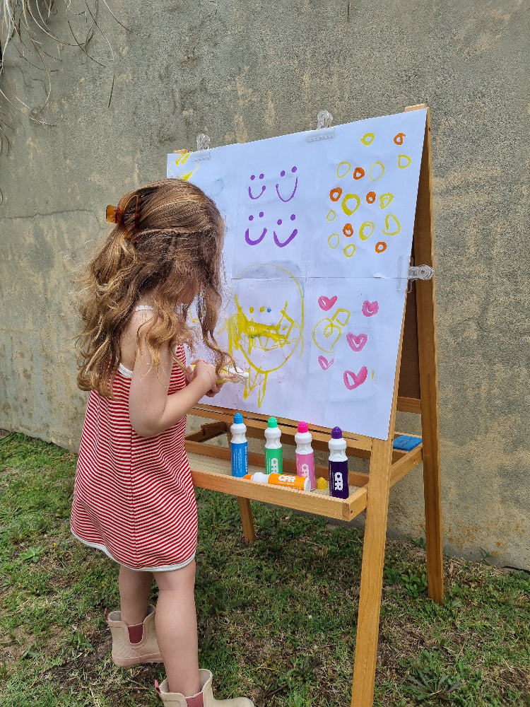 girl painting with CPR dot markers on an easel