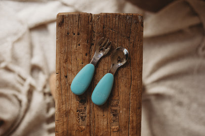 Fork and spoon with blue silicone handles on a wooden surface