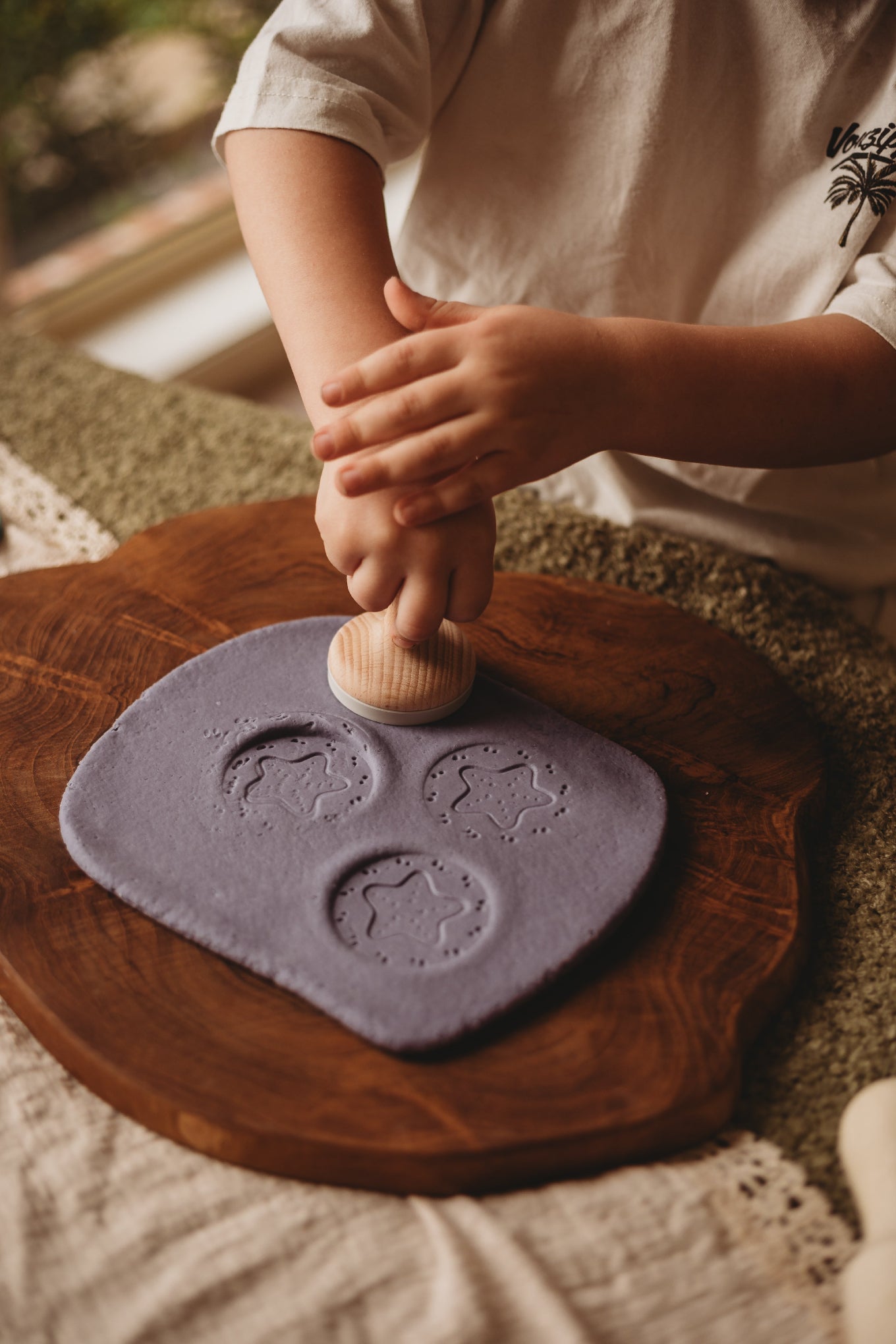 Child pressing sea creature stamp into purple playdough