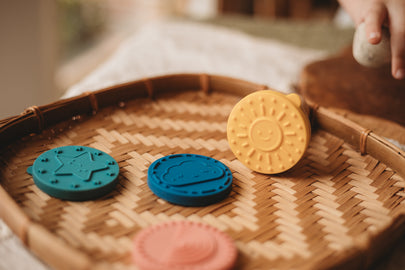 Colourful silicone stampers on a woven tray with a blurred background