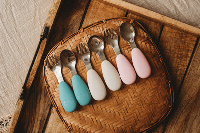Set of colorful children's cutlery on a woven tray