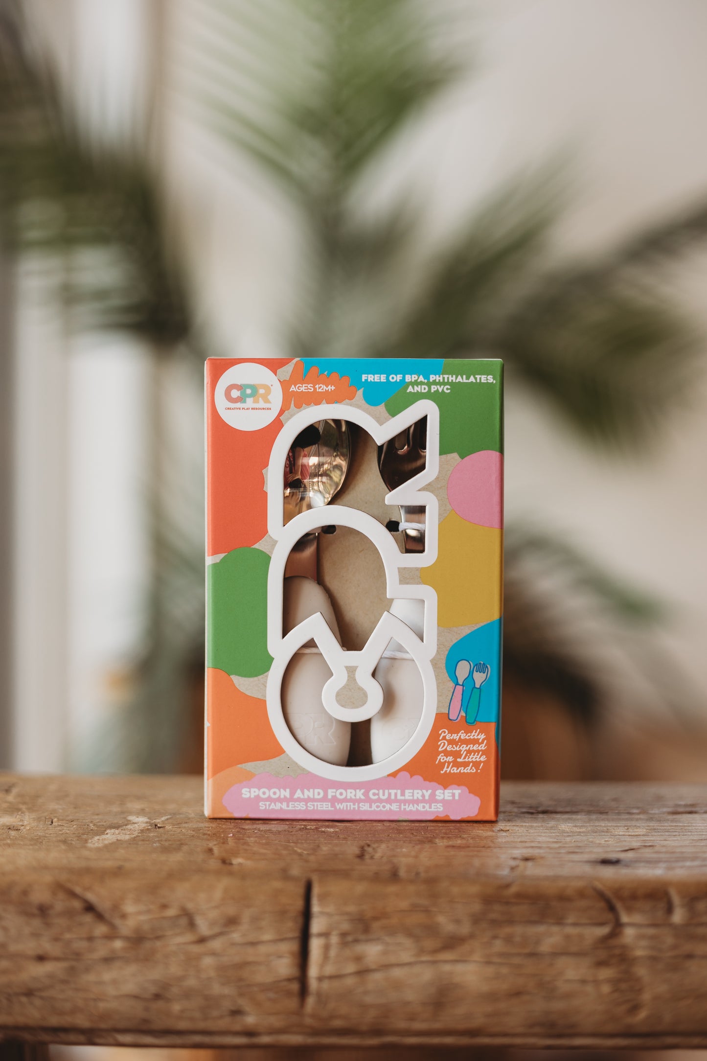 Colorful packaging of a product on a wooden surface with blurred greenery in the background