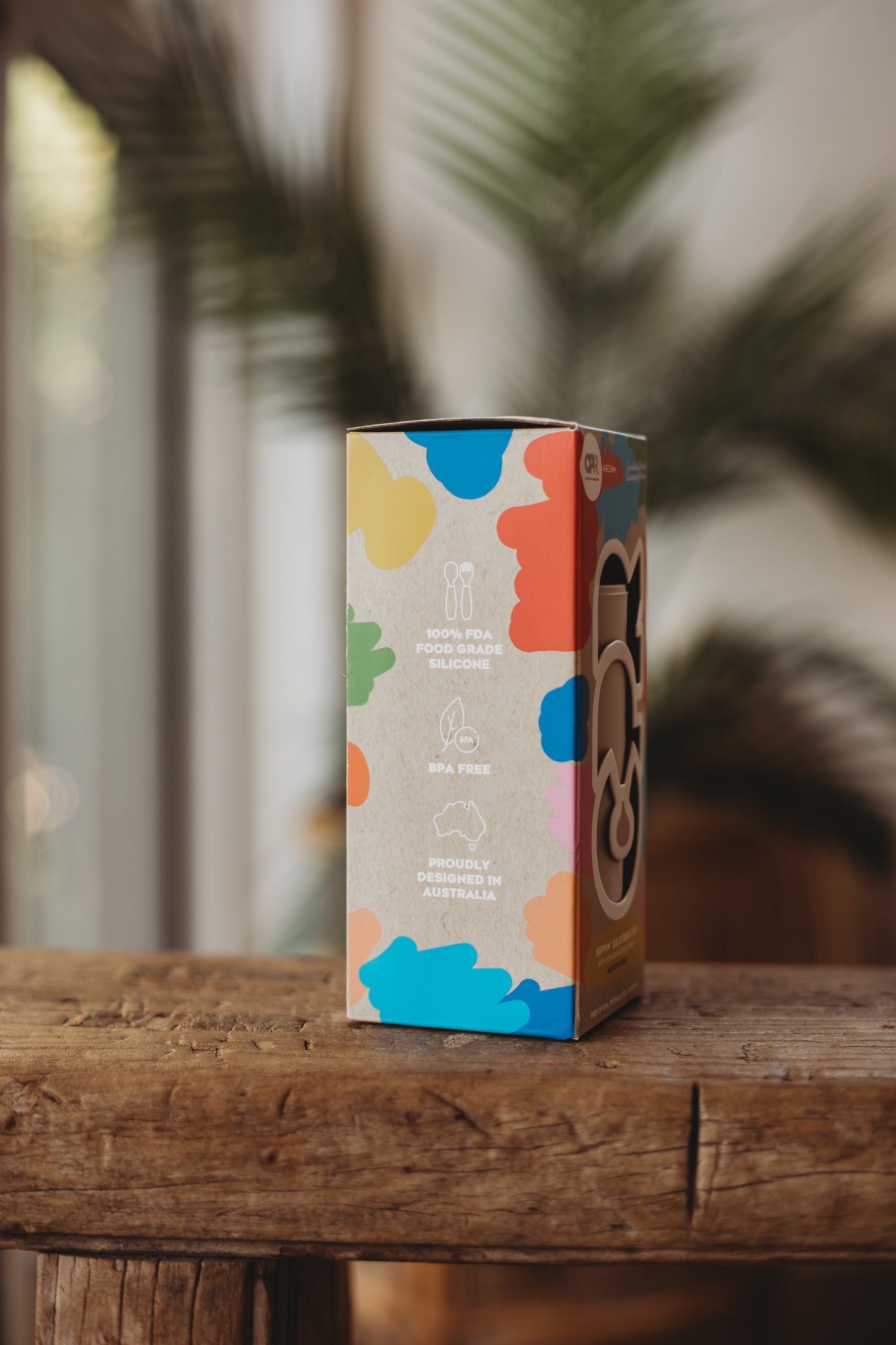 Colorful product packaging on a wooden surface with a blurred natural background