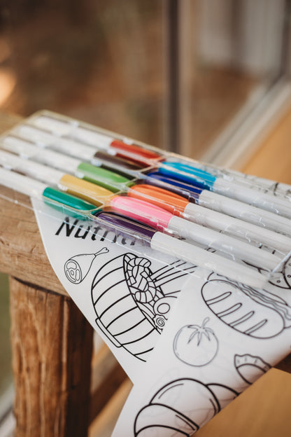 Set of markers with a colouring mat on a wooden surface