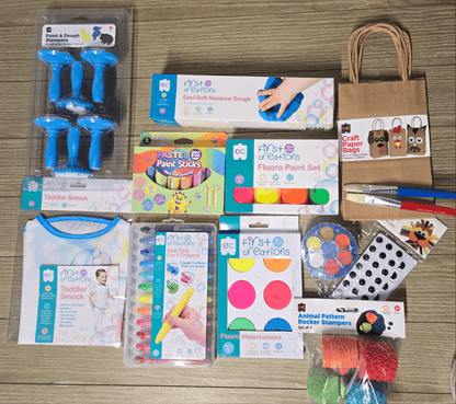 Assorted art supplies including paint sticks, stampers, and paper bags on a wooden surface.