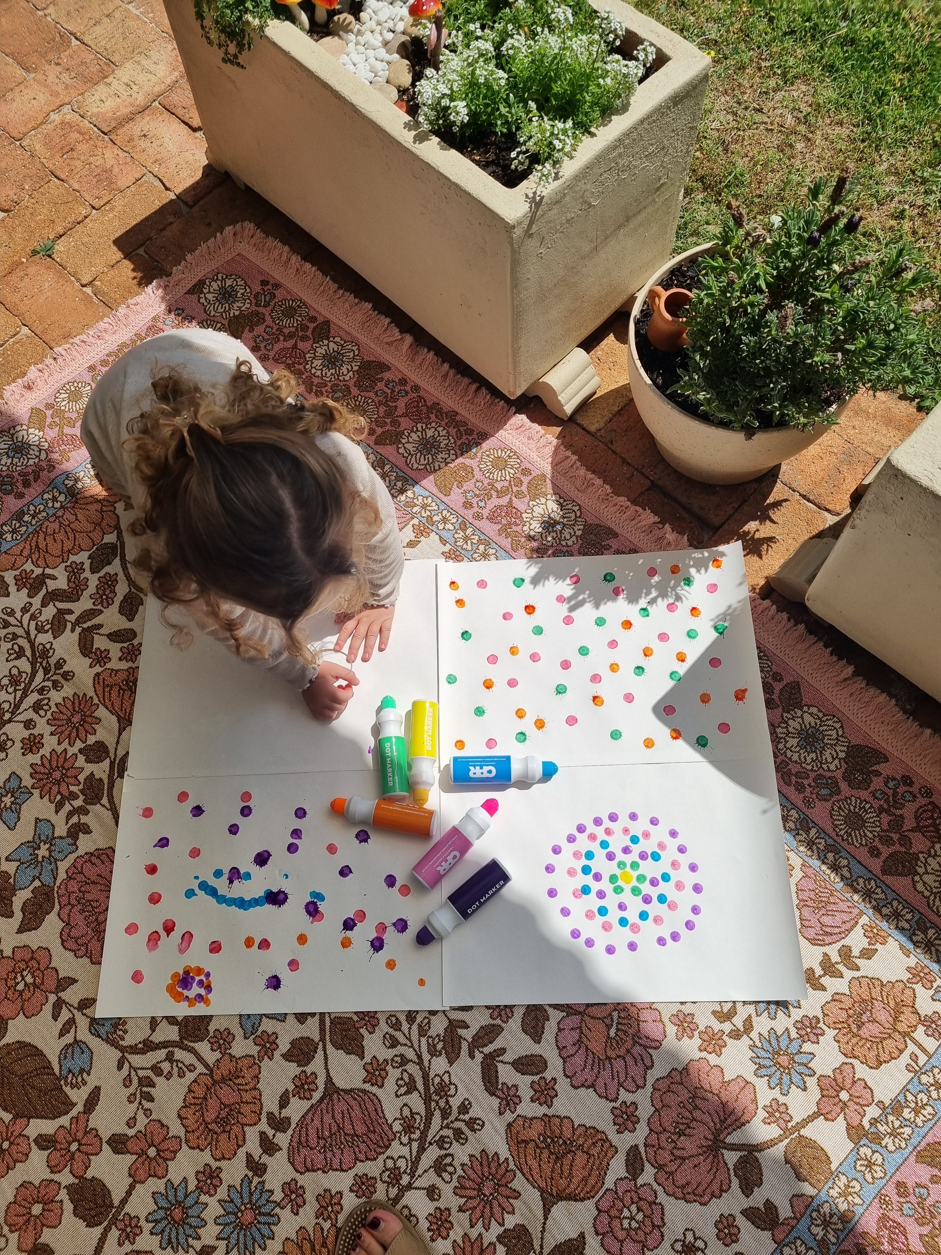 child sitting on floor using dot markers to dot and draw