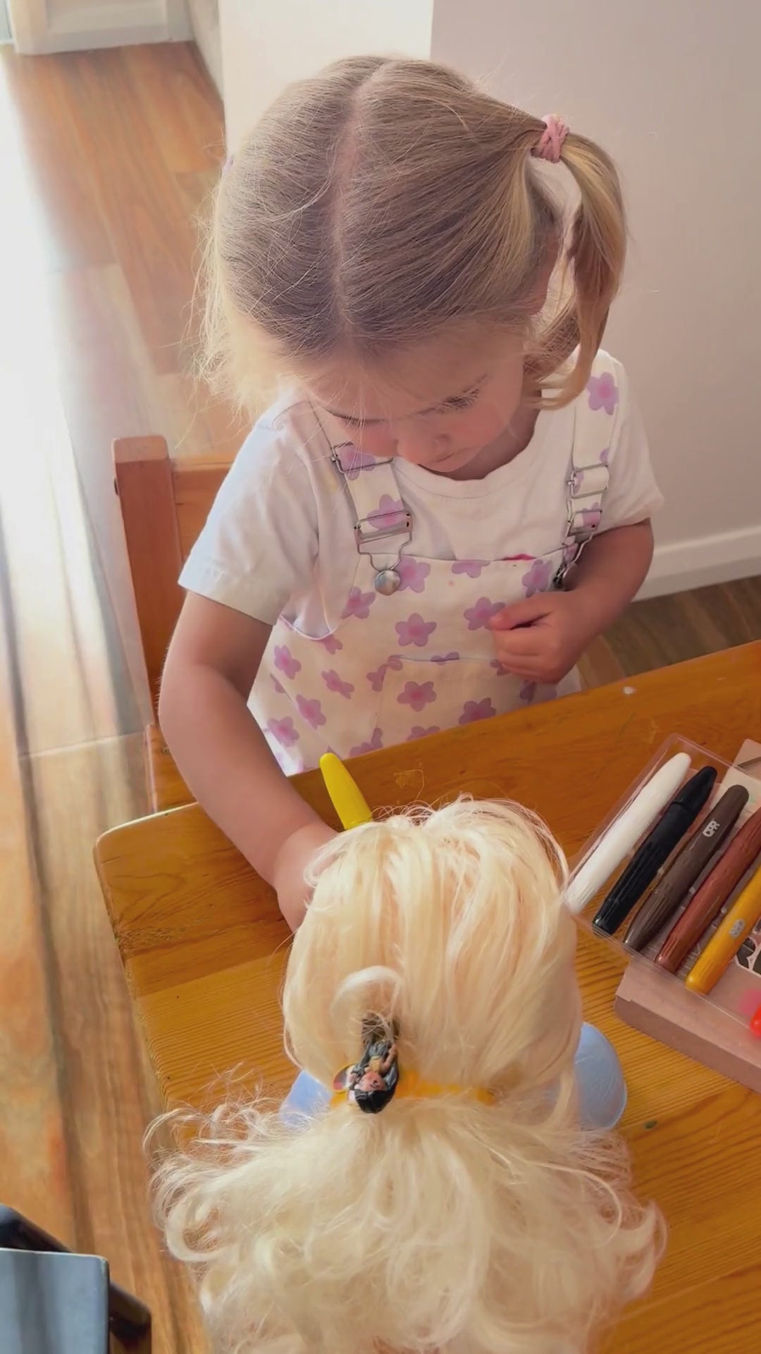 girl drawing with face paint sticks on dolls and her face